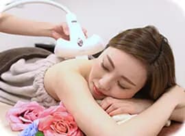 学生が背中の脱毛の施術をサロンで受けている様子の写真